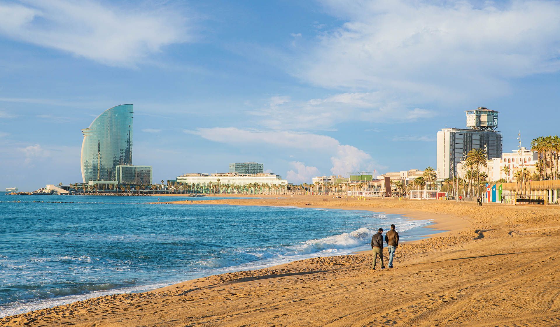 Pedestrians walk along Barceloneta Beach in Barcelona at sunrise © Shutterstock